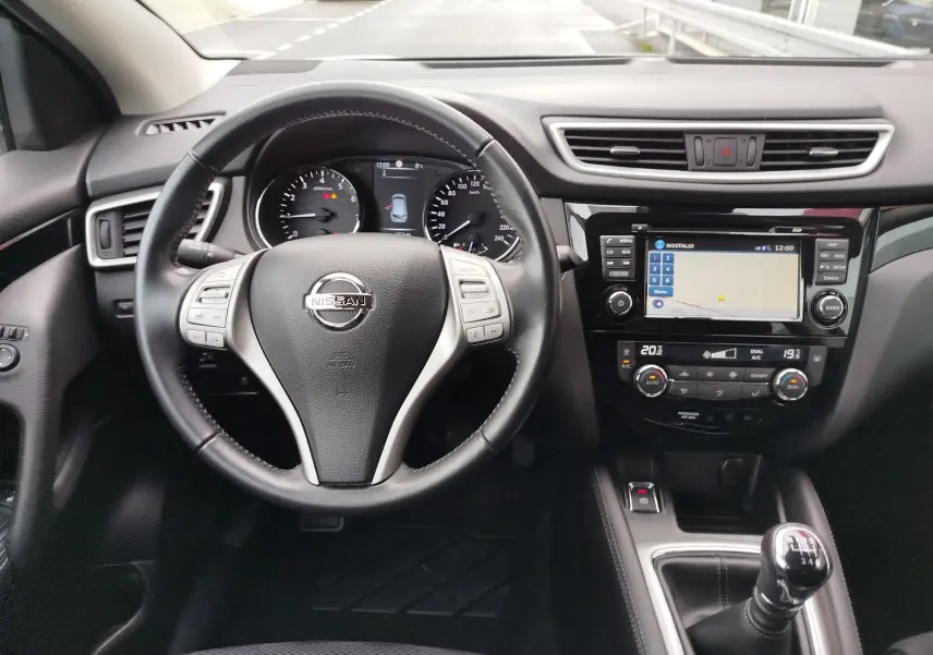 Vue intérieure frontale du tableau de bord du Nissan Qashqai 2017, avec volant cuir noir et console centrale équipée d’un écran tactile.