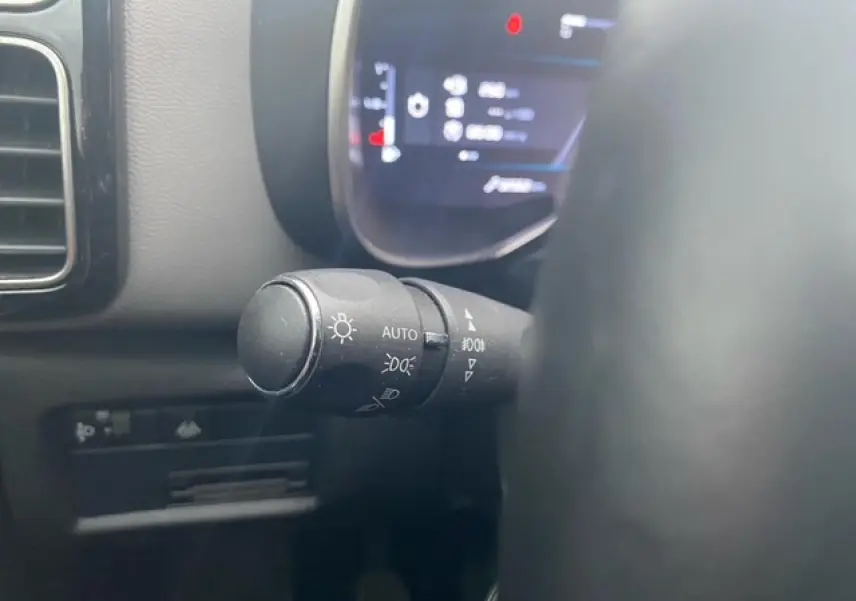 Gros plan sur la commande des feux avec affichage numérique flou du tableau de bord d'un Citroën C5 Aircross 2021.