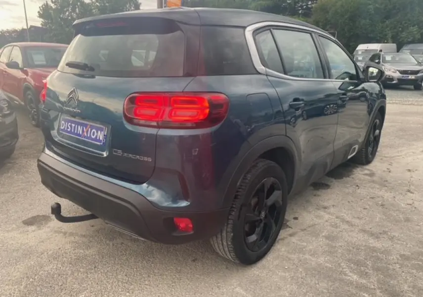 Vue 3/4 arrière droite d'un Citroën C5 Aircross bleu métallisé avec toit noir et attelage col de cygne.