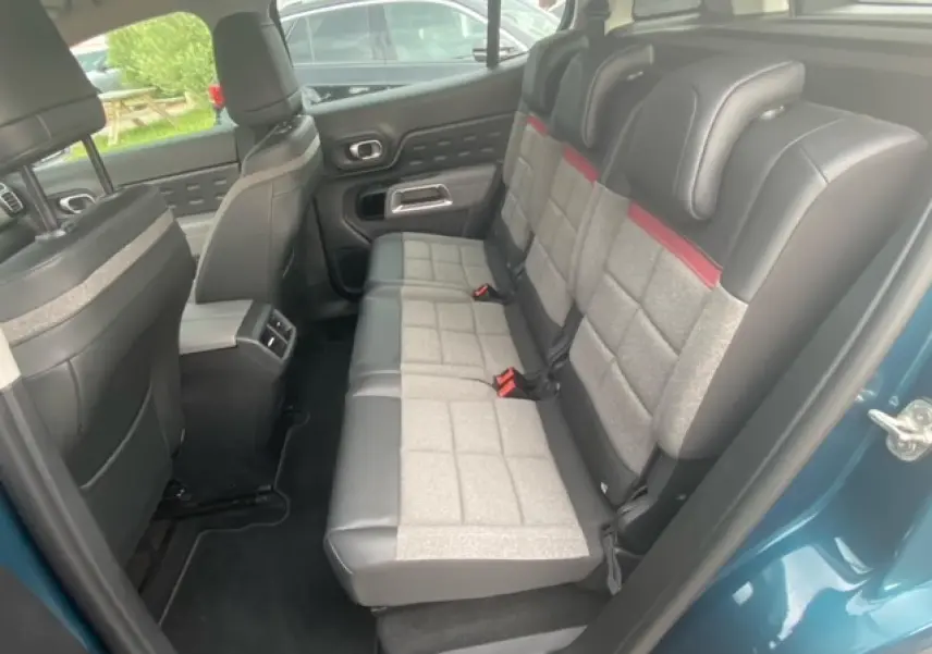 Vue intérieure côté arrière droit du Citroën C5 Aircross bleu toit noir, montrant les sièges arrière bi-matière gris et cuir noir.