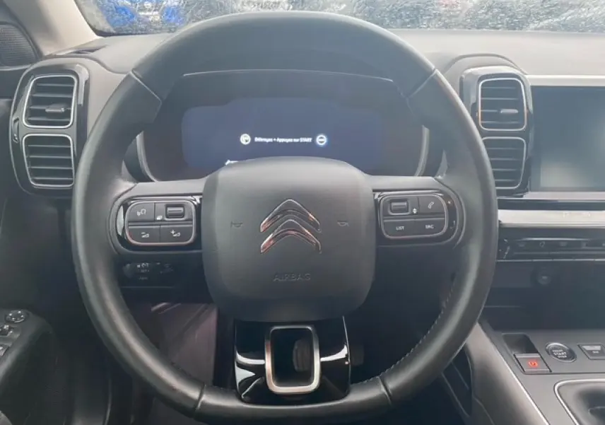 Vue rapprochée du volant cuir noir du Citroën C5 Aircross 2021 avec commandes intégrées et tableau de bord numérique.