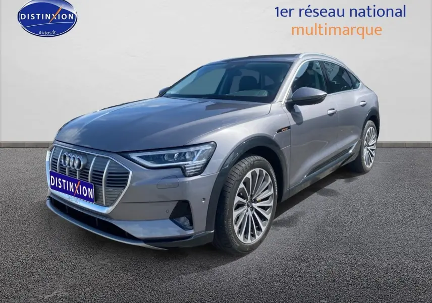 Audi Q8 E-TRON gris en 3/4 avant droit, avec calandre distinctive et jantes alu multibranches visibles.