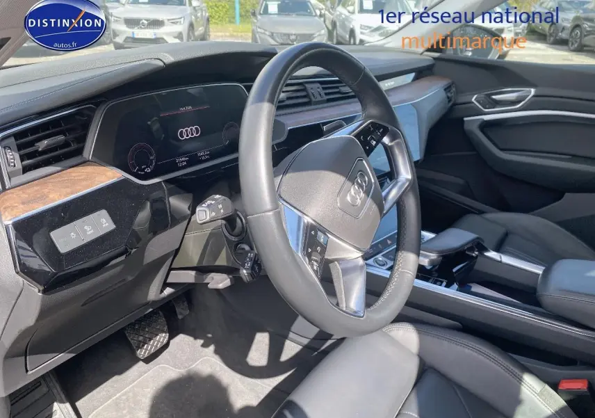 Vue intérieure côté conducteur de l'Audi Q8 E-TRON 55 408 avus quattro 2022, volant cuir et tableau de bord numérique.