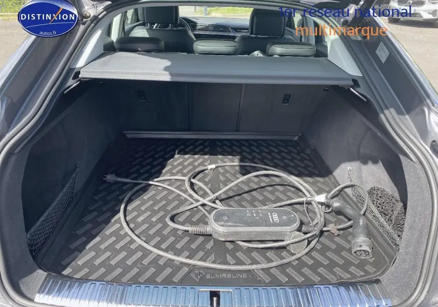 Coffre ouvert d’un Audi Q8 E-TRON gris, vue arrière montrant le câble de recharge électrique dans le compartiment.