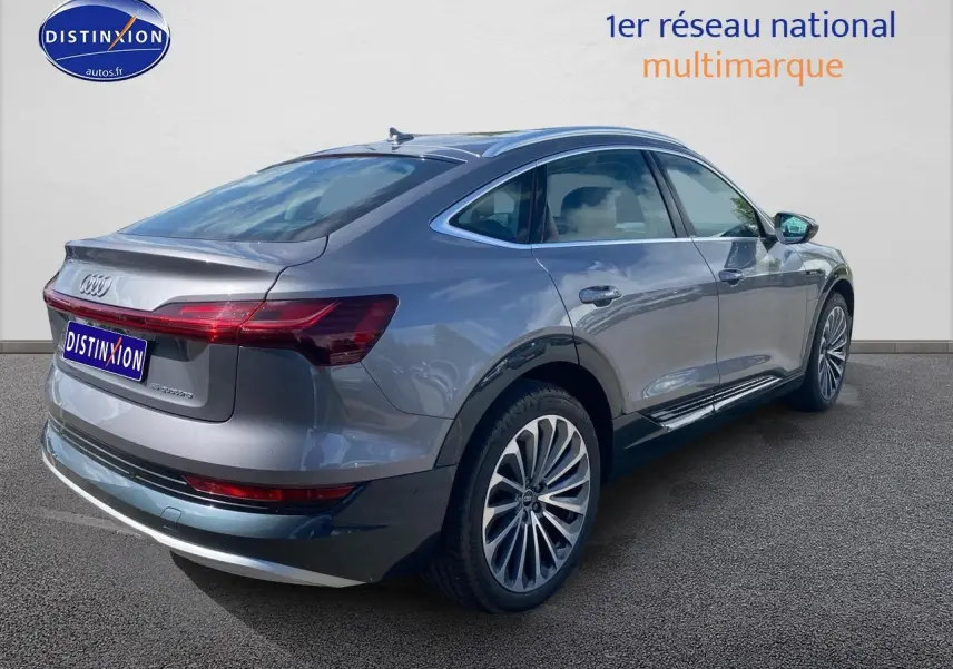 Audi Q8 E-Tron gris en vue 3/4 arrière droit, soulignant ses jantes alu et sa silhouette élancée électrique.