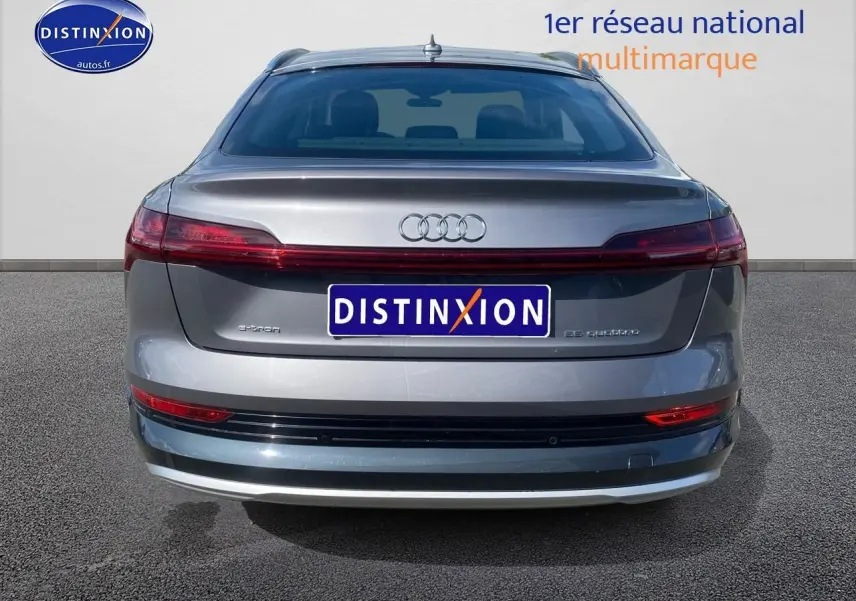 Vue arrière d'un Audi Q8 E-Tron gris 55 quattro 2022 avec feux arrière reliés et logo distinctif au centre.