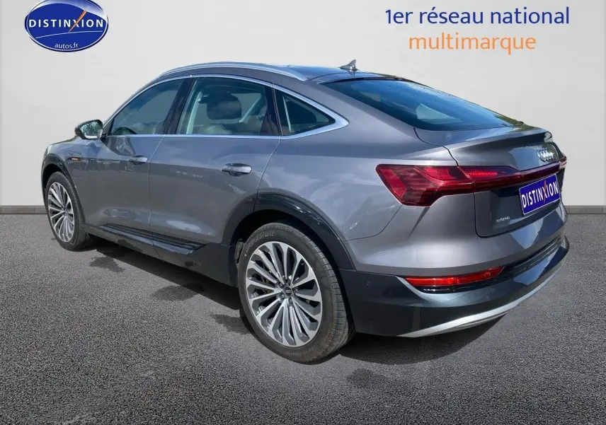 Audi Q8 E-TRON gris vu en 3/4 arrière côté gauche, soulignant ses jantes alu et feux arrière LED.