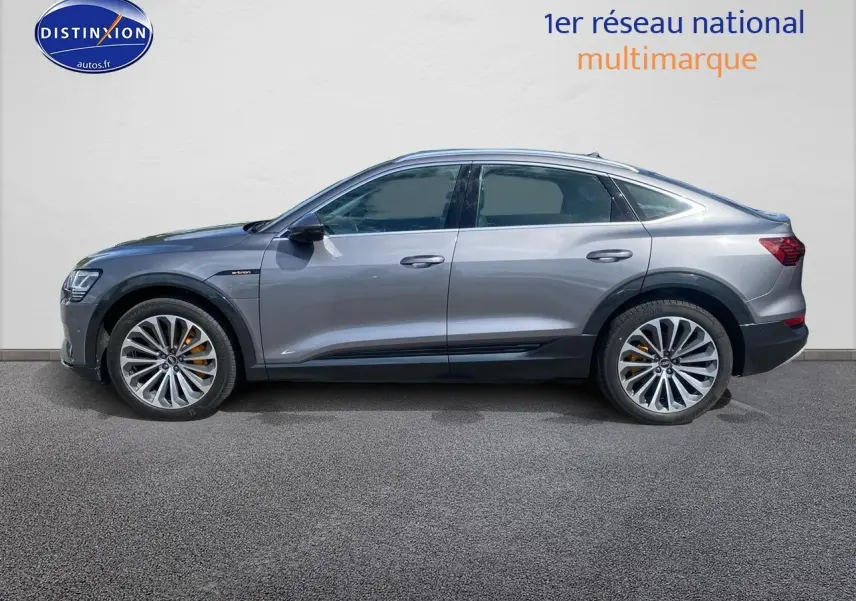 Audi Q8 E-Tron gris en vue profil côté gauche, avec jantes alu et étriers de frein orange visibles.