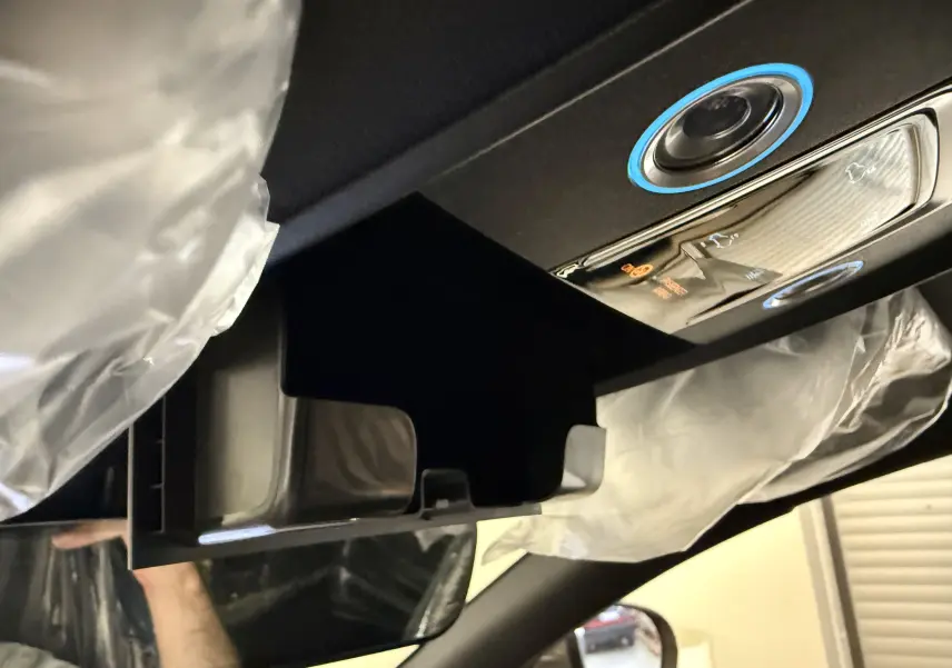 Gros plan sur le rangement ouvert au plafond côté conducteur du BYD SEAL U gris, avec commandes éclairées et airbags visibles.