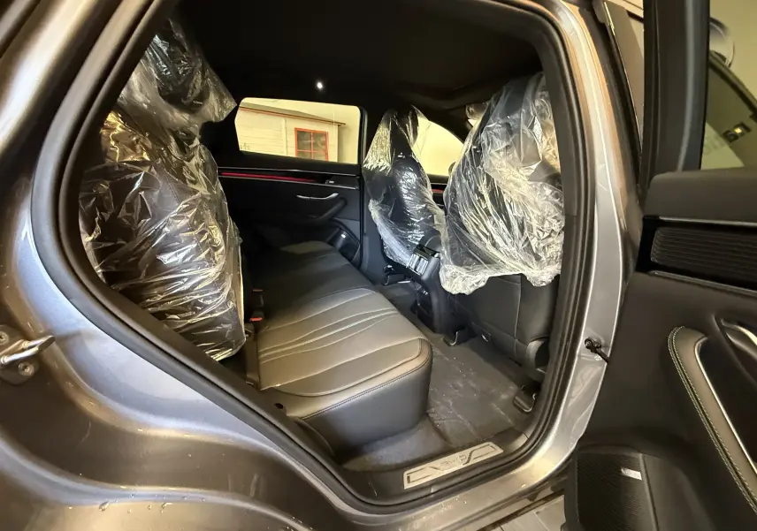 Vue intérieure côté gauche arrière du BYD SEAL U gris, montrant les sièges arrière en cuir protégés par des housses plastiques.