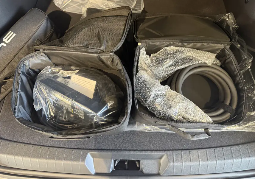 Vue plongeante sur le coffre gris du BYD SEAL U avec deux sacs ouverts contenant câbles de recharge et accessoires.