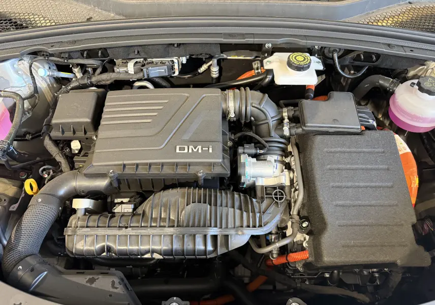 Vue plongeante sur le moteur hybride rechargeable gris du BYD SEAL U 1.5l DM-i avec détails des composants et câbles orange.
