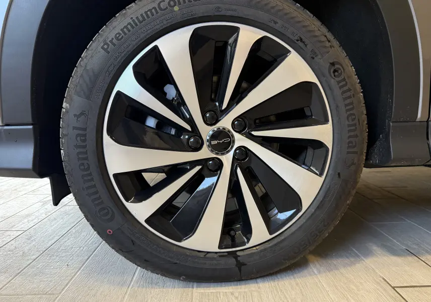 Gros plan sur la jante bicolore noir et argent d’une BYD SEAL U gris, soulignant le logo BYD au centre.