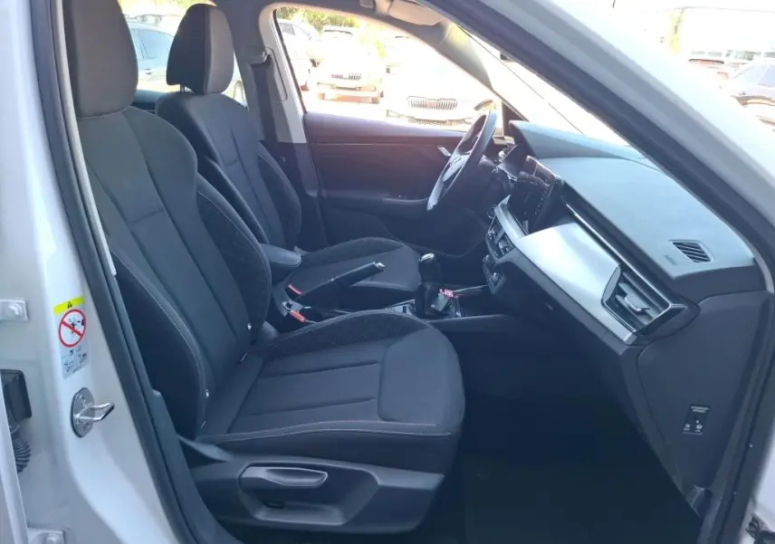 Vue intérieure côté conducteur du Skoda Kamiq blanc 2022, sièges noirs avec console centrale et tableau de bord digital.