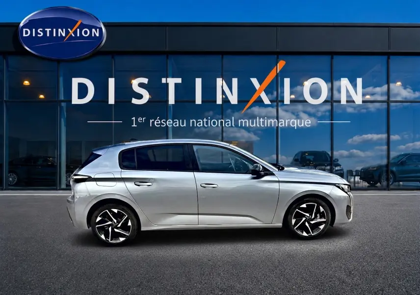 Profil droit de la Peugeot 308 1.2 hybrid 145 allure e-dcs6 gris artense avec jantes alliage modernes devant un bâtiment Distinxion.