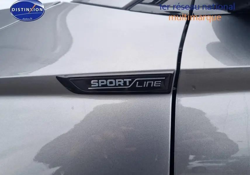 Gros plan sur l'emblème Sportline sur la portière gris graphite du Skoda Karoq 2025 côté avant droit.