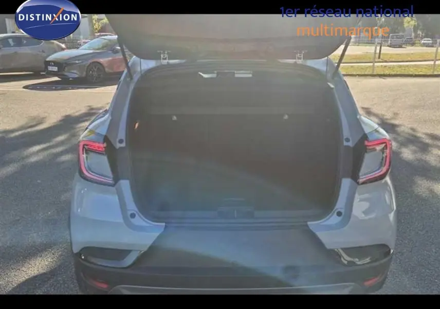 Vue arrière du Renault Captur E-Tech hybride gris Rafale avec coffre ouvert, mettant en valeur ses feux LED distinctifs.