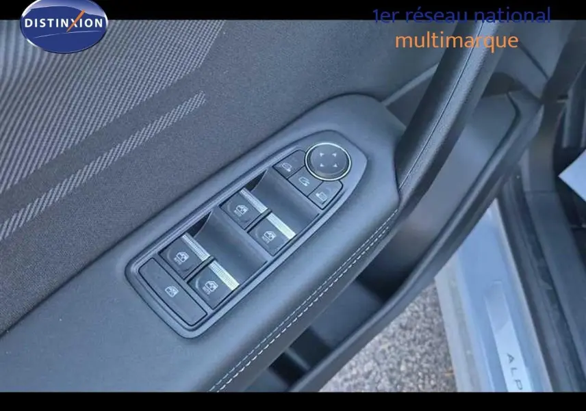 Gros plan sur les commandes des vitres électriques et rétroviseurs sur la porte côté conducteur d’un Renault Captur gris Rafale.