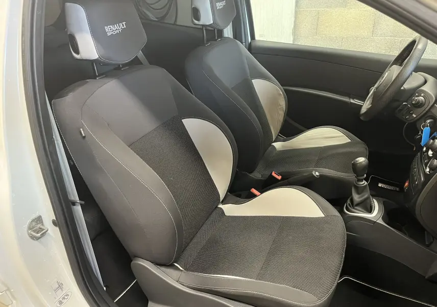 Vue intérieure côté gauche des sièges avant noirs et gris avec logo Renault Sport sur appuie-tête dans une Renault Clio III RS 20th Anniversary.