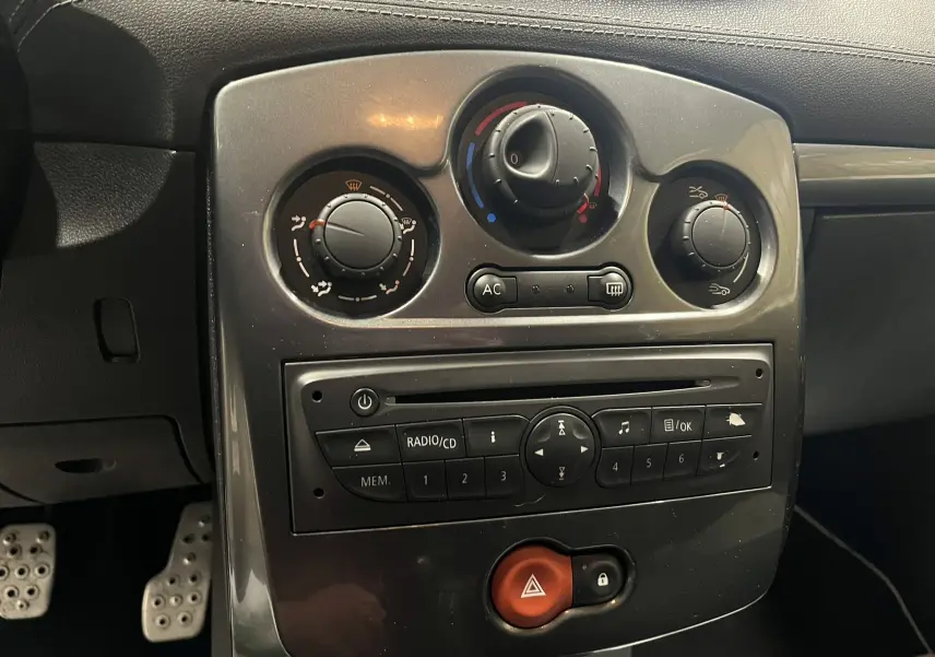 Vue rapprochée du tableau de bord central de la Renault Clio III RS 20th Anniversary avec commandes de climatisation et radio intégrée.