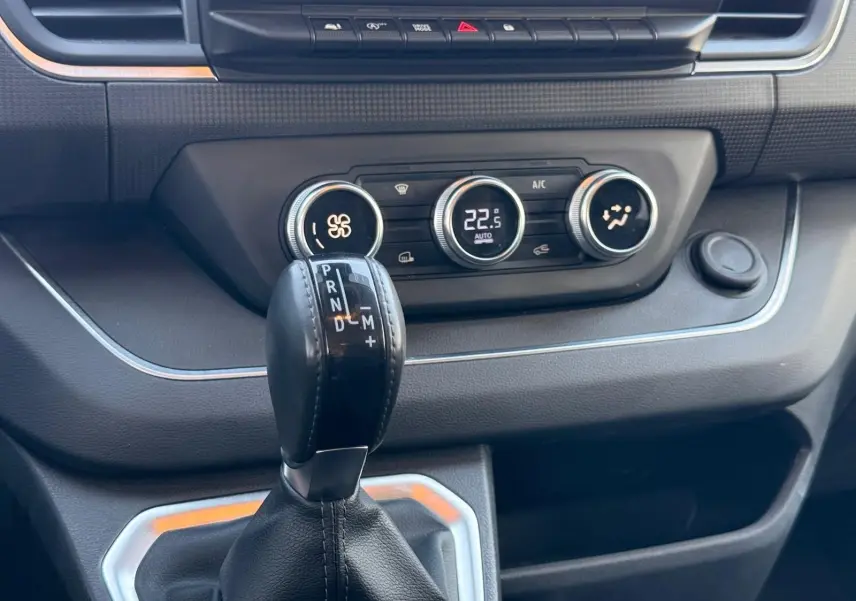 Gros plan sur la console centrale du Renault Trafic gris, avec levier de boîte automatique et commandes de climatisation.