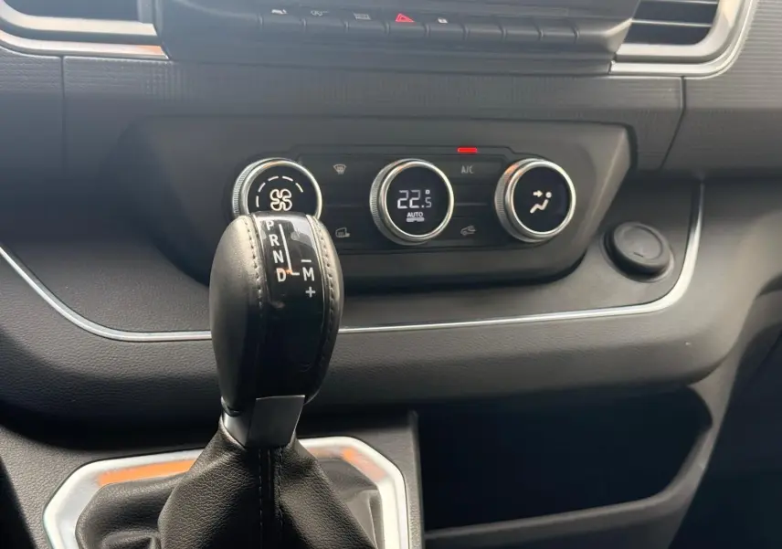 Gros plan sur la commande de boîte automatique et les réglages climatiques du tableau de bord du Renault Trafic gris.