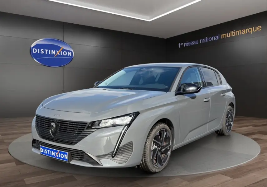 Peugeot 308 Hybrid gris foncé vue 3/4 avant droite, avec calandre noire et phares LED distinctifs.