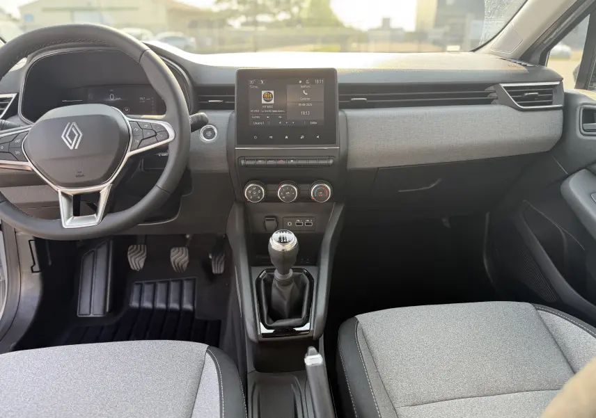 Intérieur de Renault Clio 1.5 DCI 2025, vue frontale du tableau de bord avec volant, écran tactile et levier de vitesses manuel.