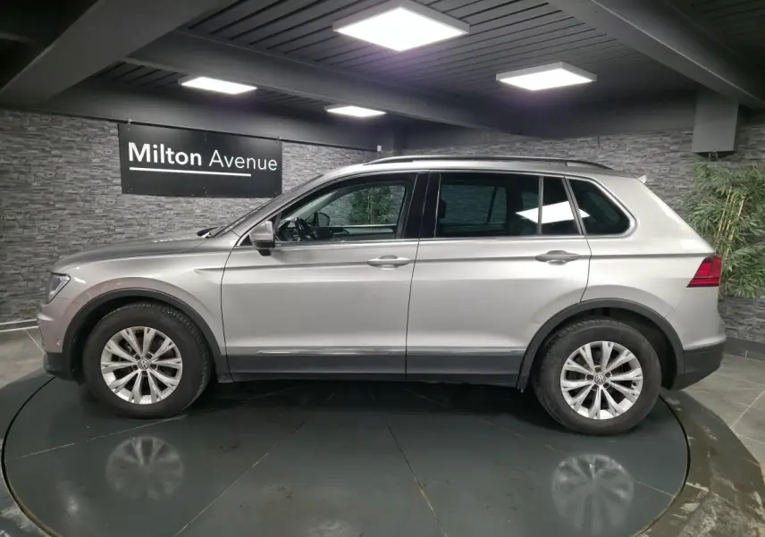 Vue latérale droite d'un Volkswagen Tiguan gris métallisé 2018 en intérieur avec jantes alliage 17 pouces.