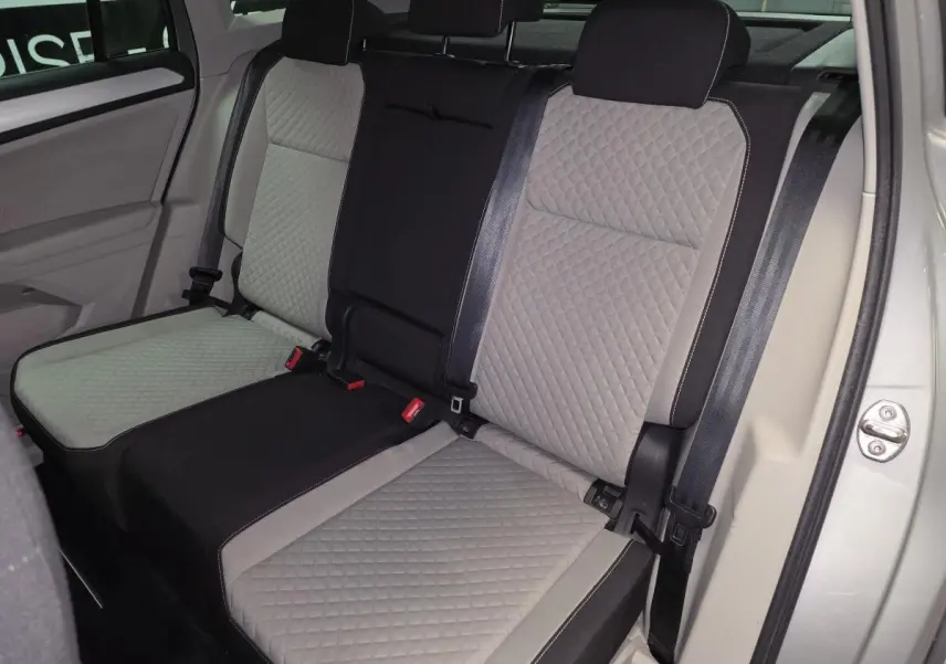 Vue intérieure sur les sièges arrière gris à motif losange du Volkswagen Tiguan 2018, avec ceintures de sécurité visibles.