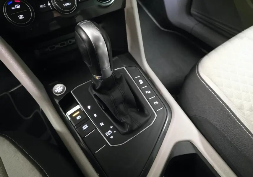Gros plan sur le levier de vitesses automatique noir et cuir du Volkswagen Tiguan gris, avec console centrale et siège tissu clair.
