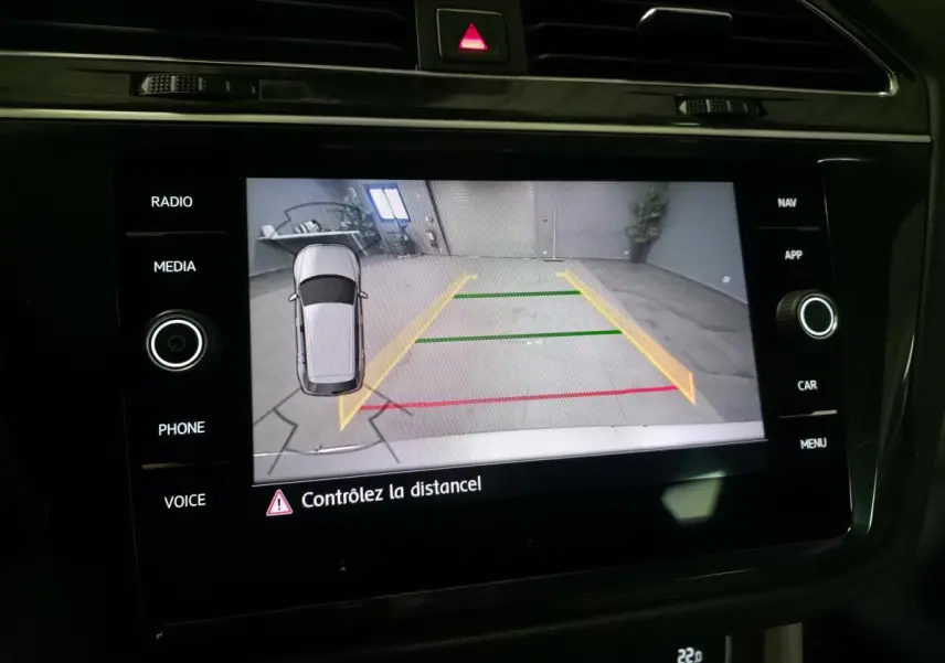 Écran de caméra de recul du Volkswagen Tiguan gris, affichant les lignes d’aide au stationnement en intérieur.