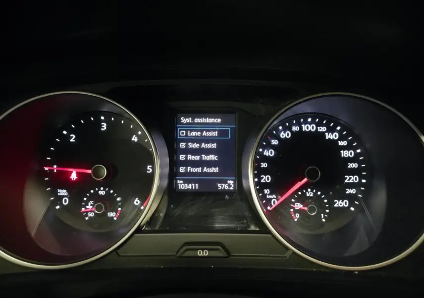 Vue rapprochée du tableau de bord du Volkswagen Tiguan gris, affichant les compteurs et les aides à la conduite activées.