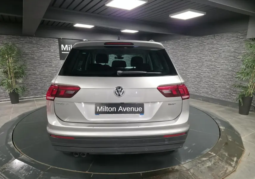 Vue arrière d'un Volkswagen Tiguan gris métallisé 2018 dans un showroom avec éclairage intérieur.