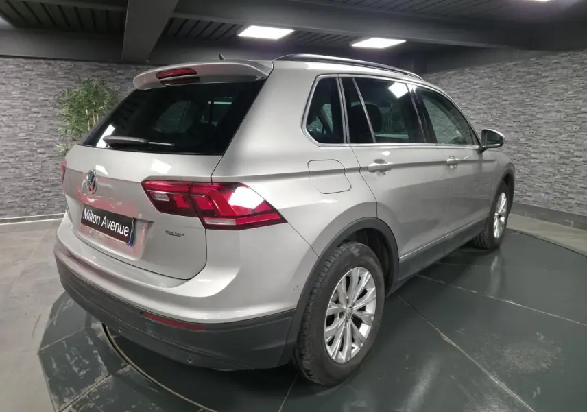 Volkswagen Tiguan gris métallisé vue 3/4 arrière droit en intérieur avec jantes alliage 17 pouces.