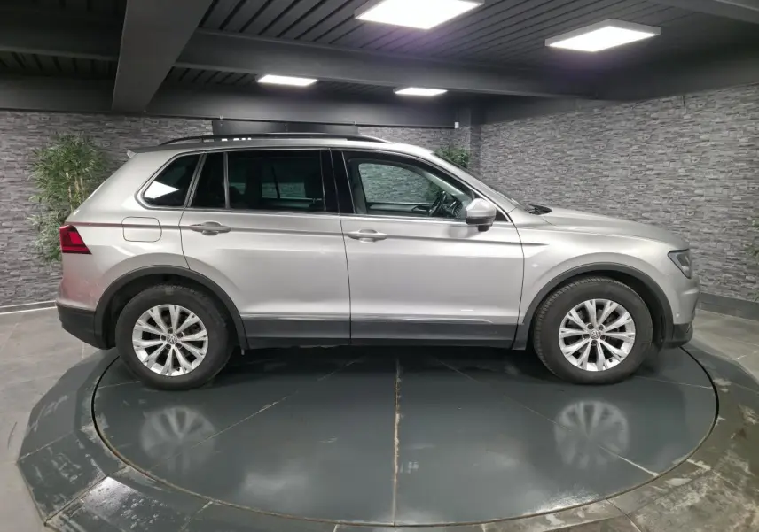 Vue latérale droite d'un Volkswagen Tiguan gris métallisé 2018 sur plateau tournant en intérieur.
