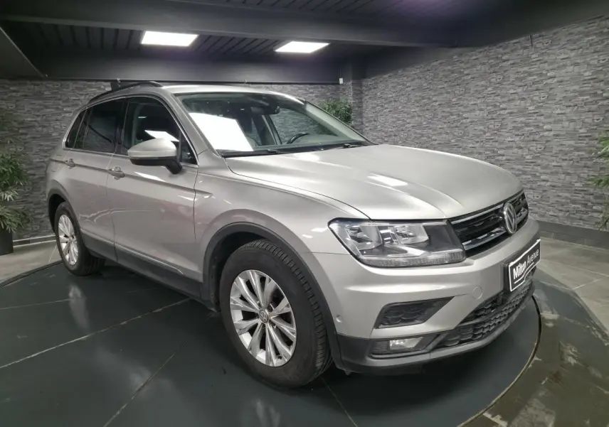 Volkswagen Tiguan gris métallisé en 3/4 avant droit, avec jantes alliage et calandre noire brillante.