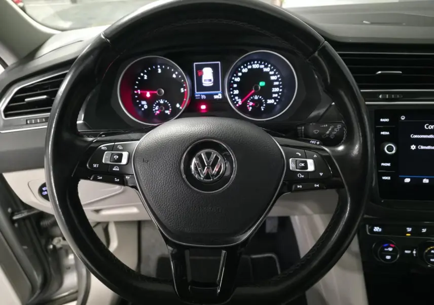 Vue rapprochée du volant cuir multifonctions noir et du tableau de bord éclairé d’un Volkswagen Tiguan gris.