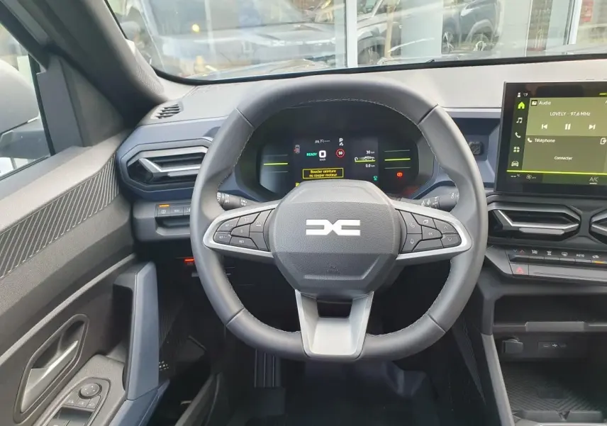Vue intérieure centrée sur le volant multifonction et le tableau de bord numérique du Dacia Duster 2026.