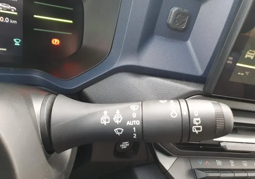 Gros plan sur la manette d’essuie-glace côté gauche du tableau de bord du Dacia Duster gris schiste 2026.