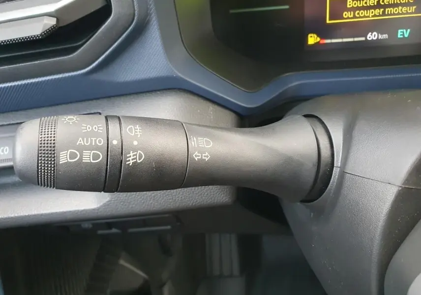 Gros plan sur la commande des feux du tableau de bord du Dacia Duster 1.6 Hybrid 140 gris schiste, affichage digital partiel.