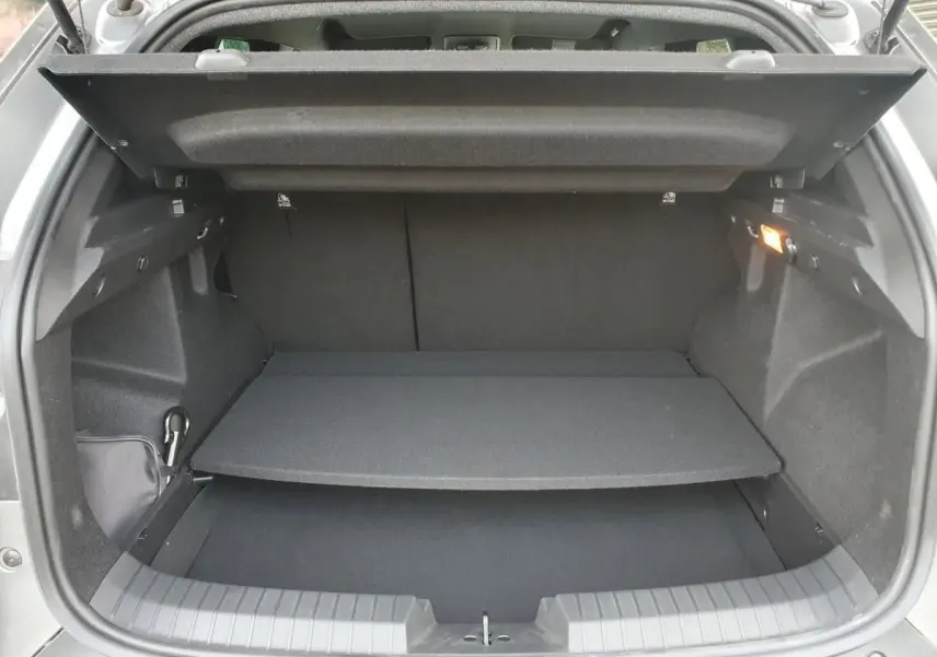 Coffre ouvert vu de l'arrière du Dacia Duster gris schiste, montrant le plancher modulable et l'éclairage intérieur.