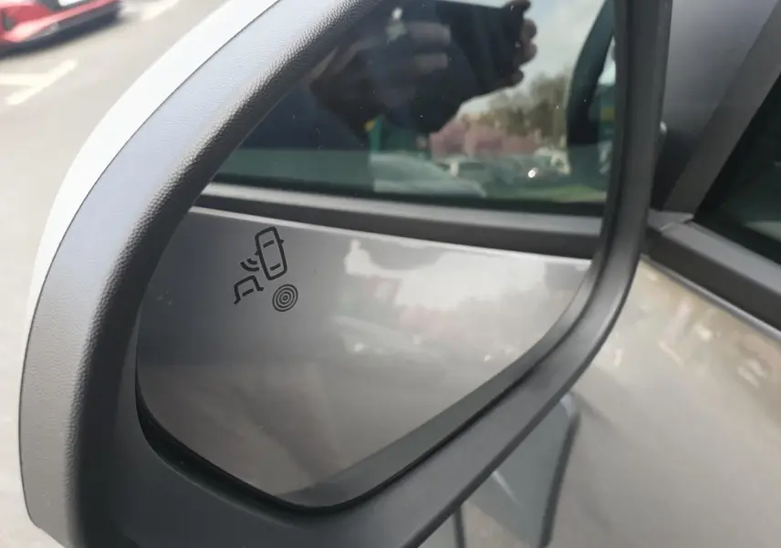 Rétroviseur extérieur côté gauche du Dacia Duster gris schiste 2026 avec indicateur d'angle mort visible.