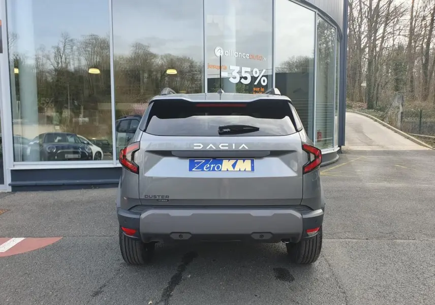 Vue arrière d'un Dacia Duster gris schiste 2026 avec feux LED et logo DACIA bien visibles.