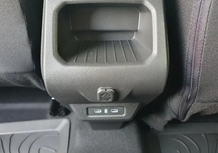 Vue rapprochée de la console arrière noire du Dacia Duster 1.6 Hybrid 140 gris schiste avec prises USB-C et prise 12V.