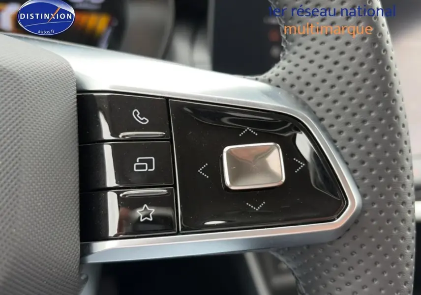 Gros plan sur les commandes multifonctions noires à gauche du volant perforé du MG ZS Hybrid blanc 2026.