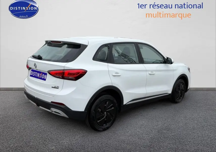 Vue 3/4 arrière droite d’un MG ZS Hybrid blanc avec jantes noires et feux arrière LED sur fond neutre.