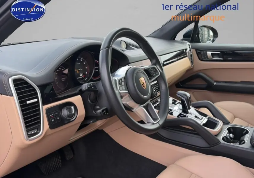 Intérieur beige et noir du Porsche Cayenne 2023, vue côté conducteur sur le volant et la console centrale.