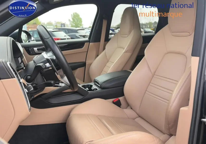 Vue intérieure côté conducteur de la Porsche Cayenne 2023 avec sièges en cuir beige et volant multifonction noir.