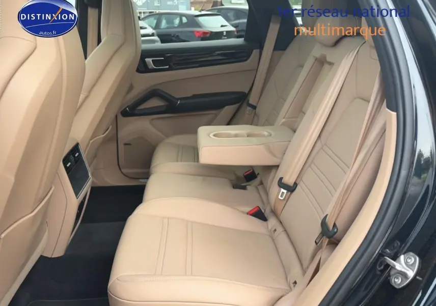 Vue côté droit de l’habitacle arrière beige d’un Porsche Cayenne 2023 avec accoudoir central et porte ouvert.